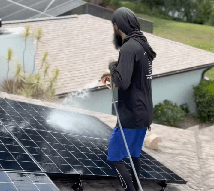 Technician soft-washing solar panels on a residential roof in Sarasota